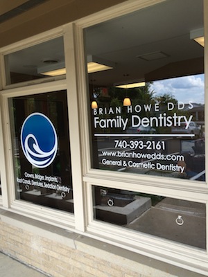 The image shows a storefront window with a sign that reads  Brian Howe DDS Family Dentistry  and includes contact information, including a phone number and website address.