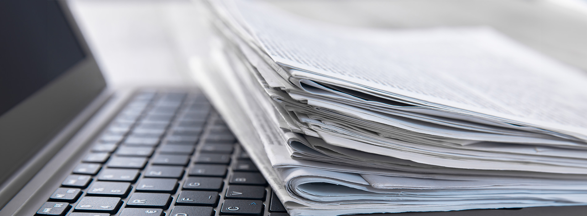 The image shows a stack of papers on top of a laptop keyboard.